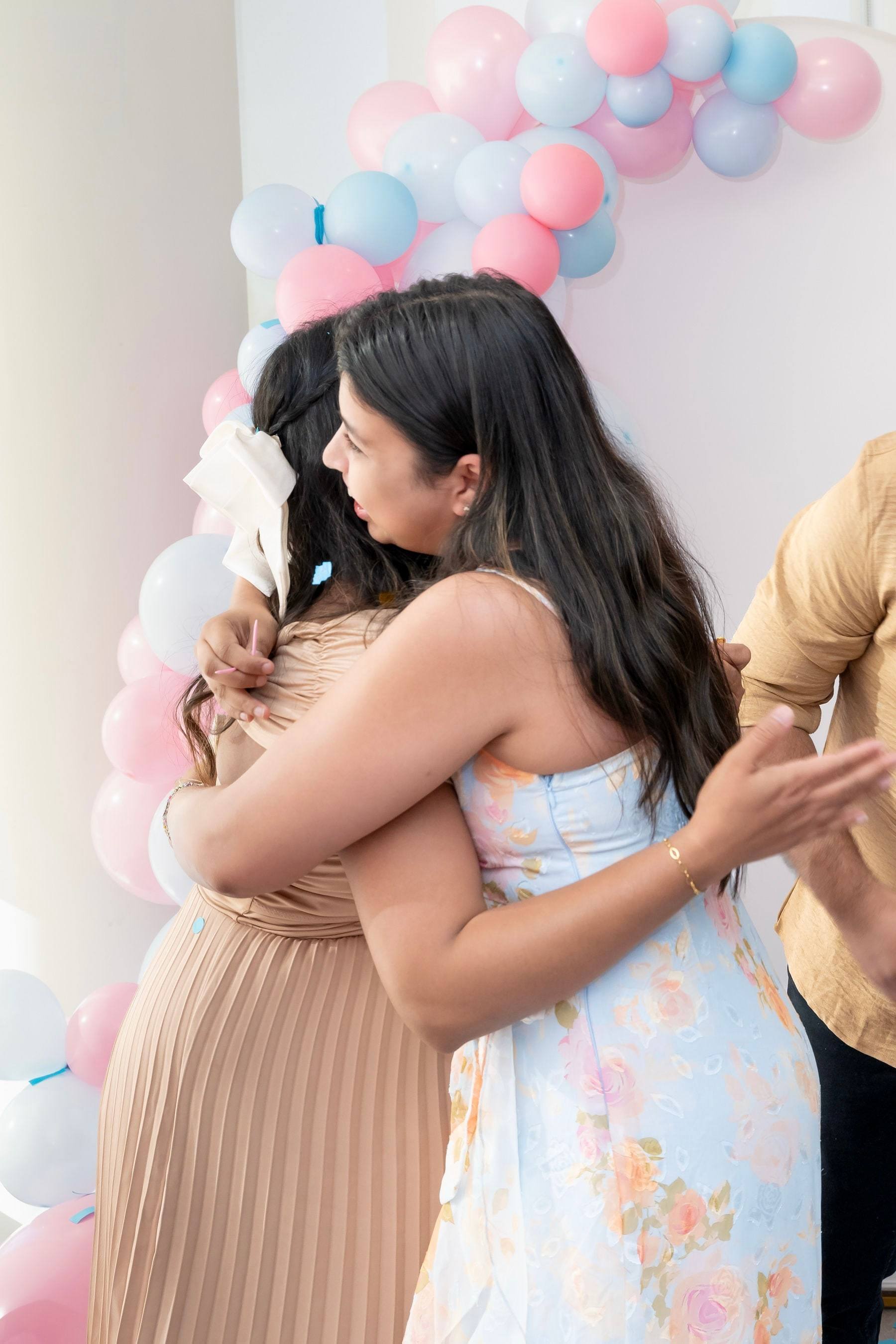 Mother-to-be hugging a guest at her gender reveal party