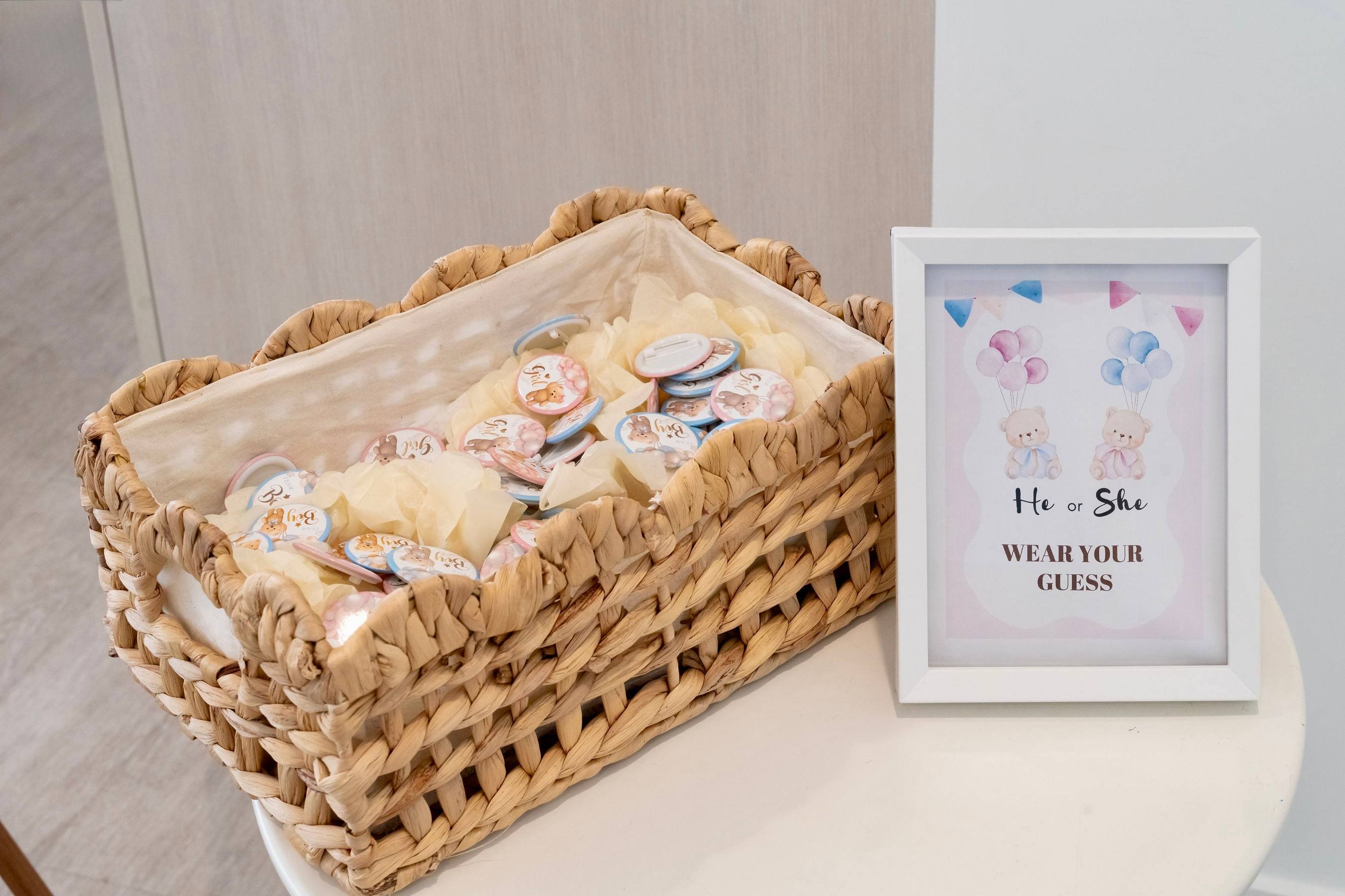 Woven basket of party favours beside a "he or she" guessing sign