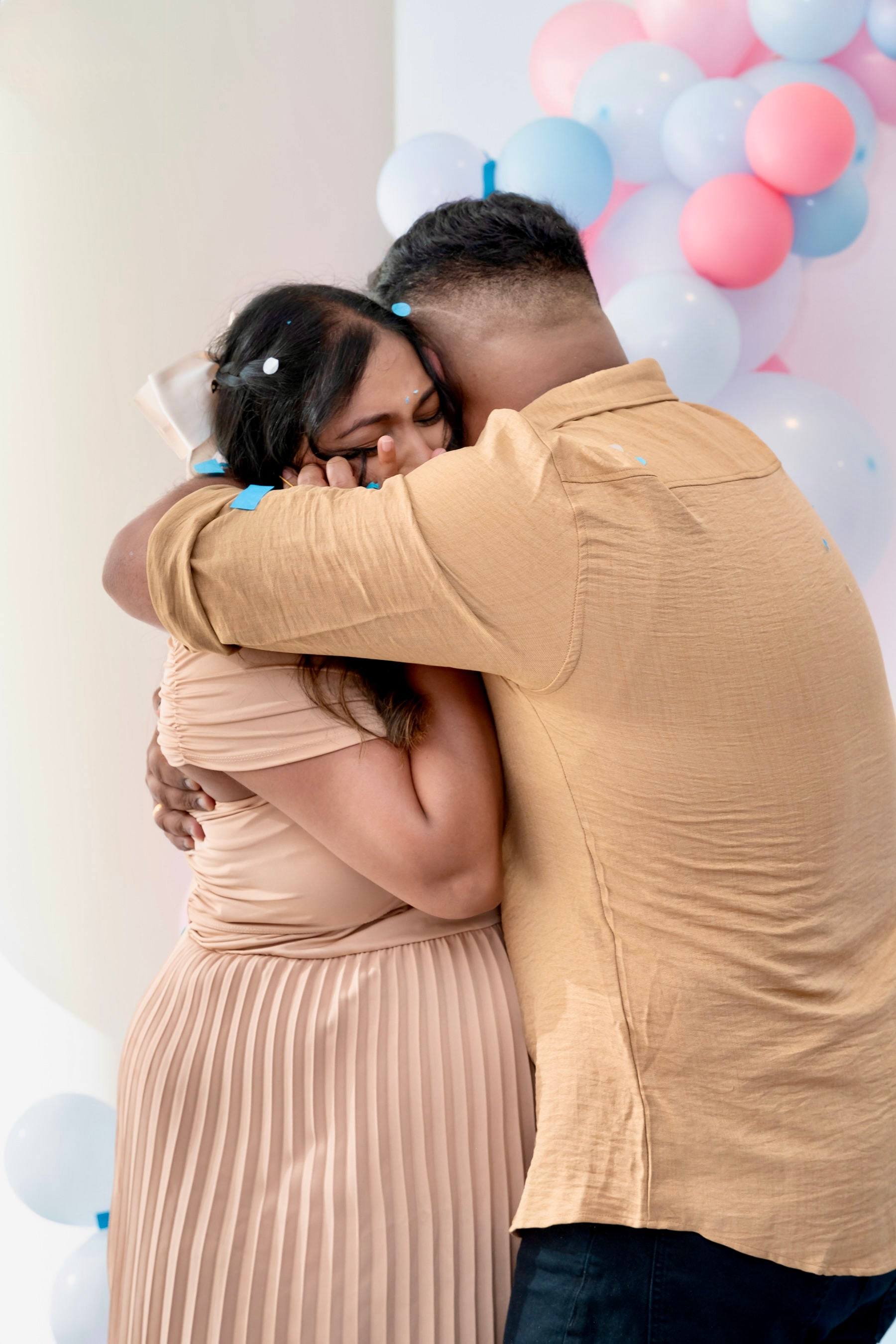 Expecting couple sharing an emotional hug at their reveal