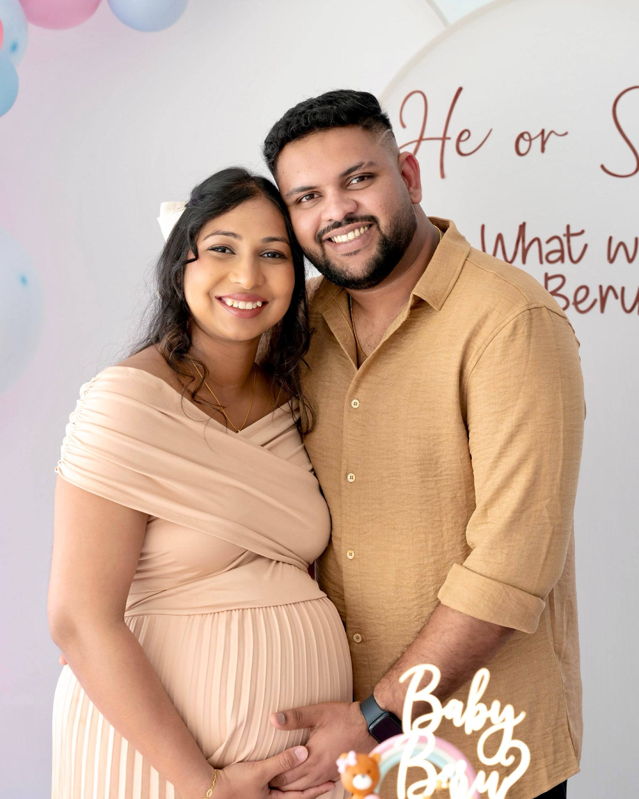 Close portrait of a smiling expecting couple with the cake topper