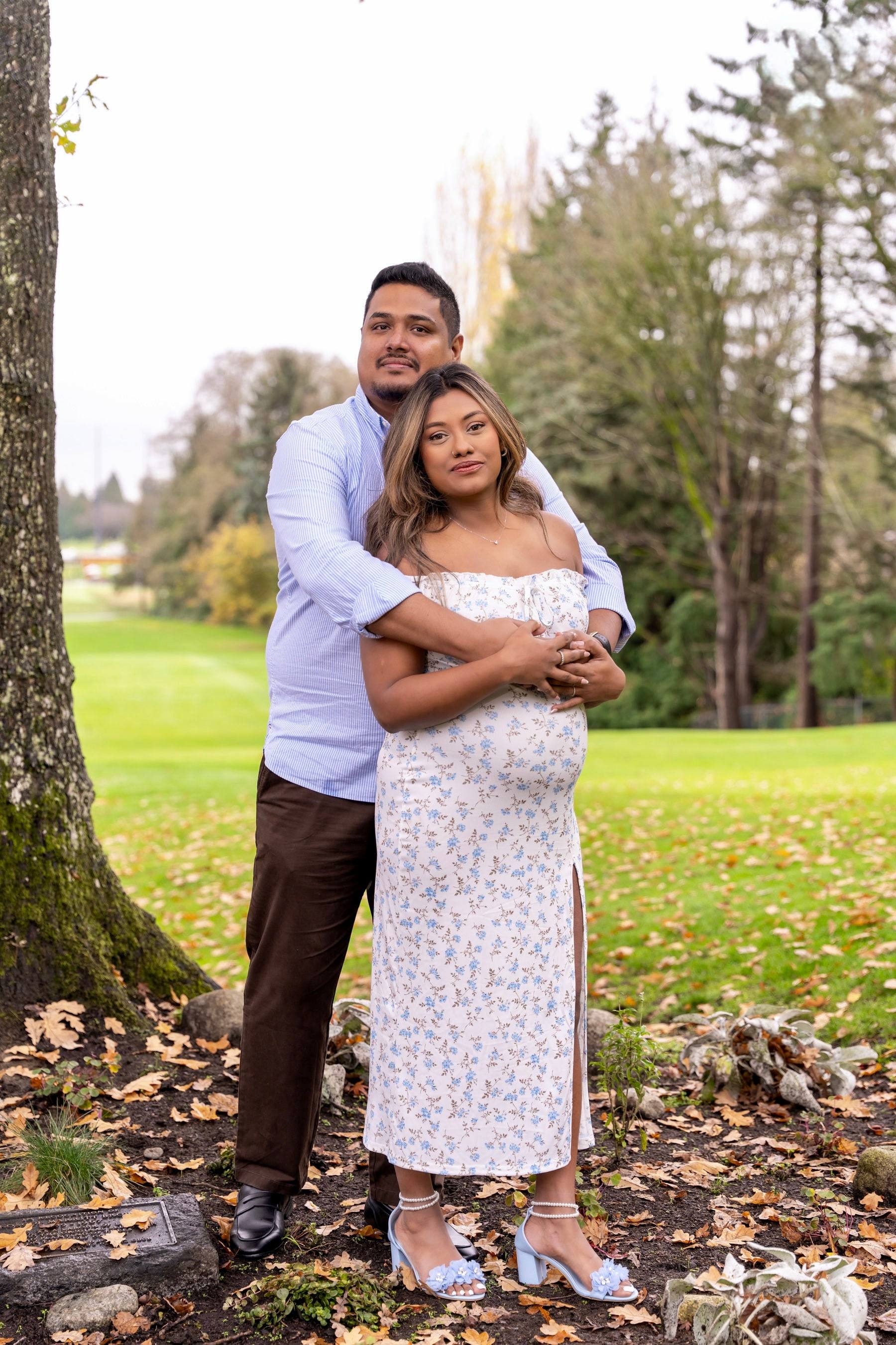 Expecting couple embracing among autumn trees on a golf course