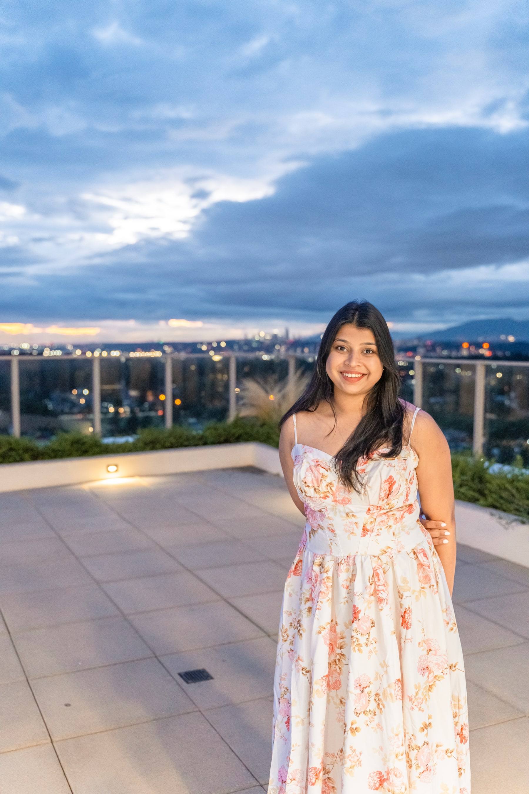 Birthday girl in a floral dress on a rooftop terrace at dusk