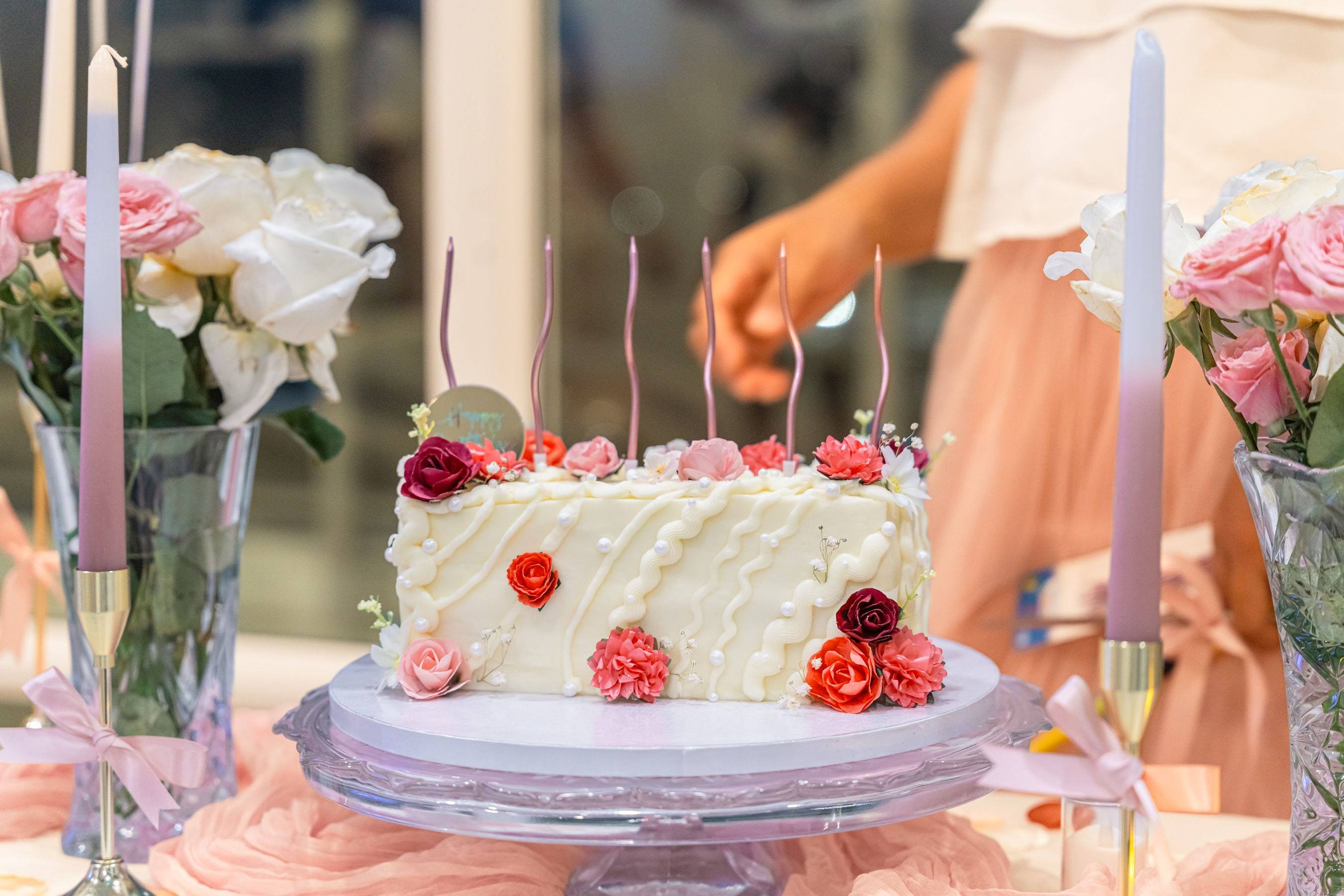 Close up of a white birthday cake with red roses and candles