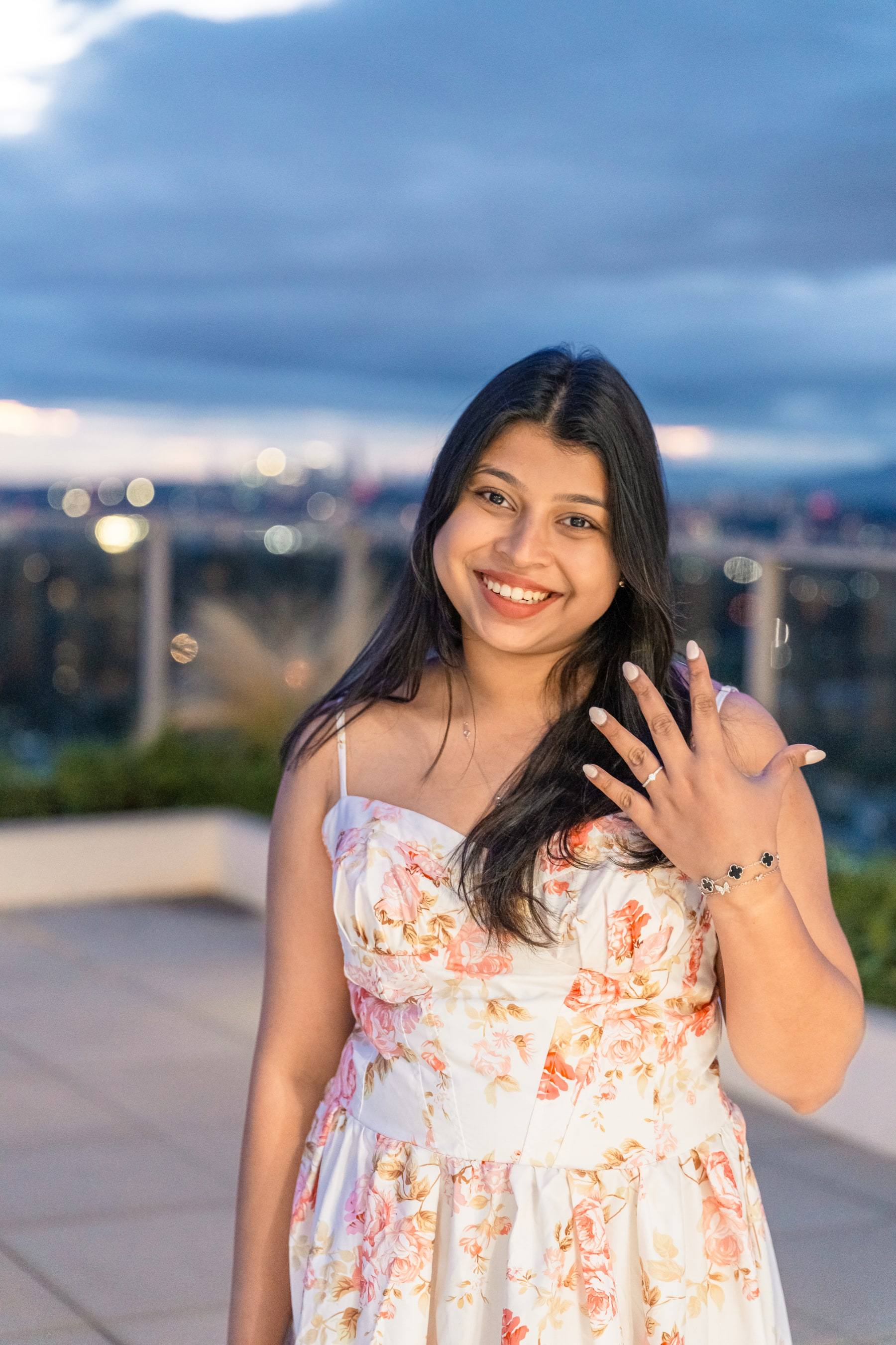 Birthday girl laughing and waving on a rooftop at sunset