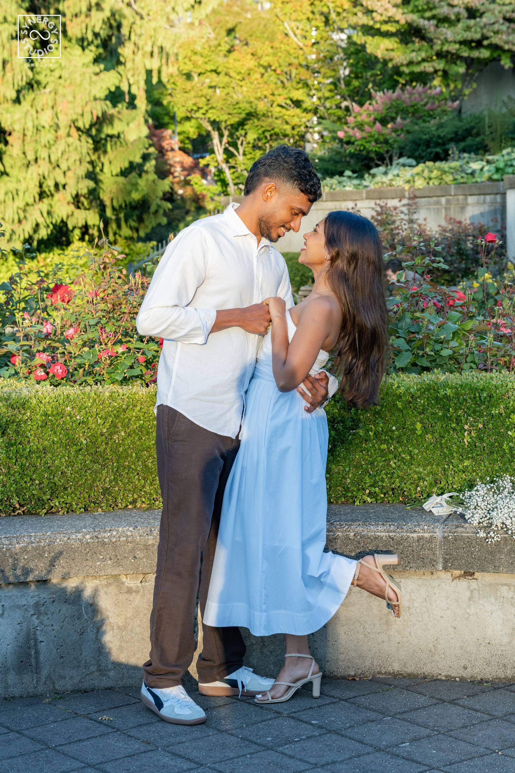 Couple kissing beside a stone wall at golden hour with sunlit trees behind