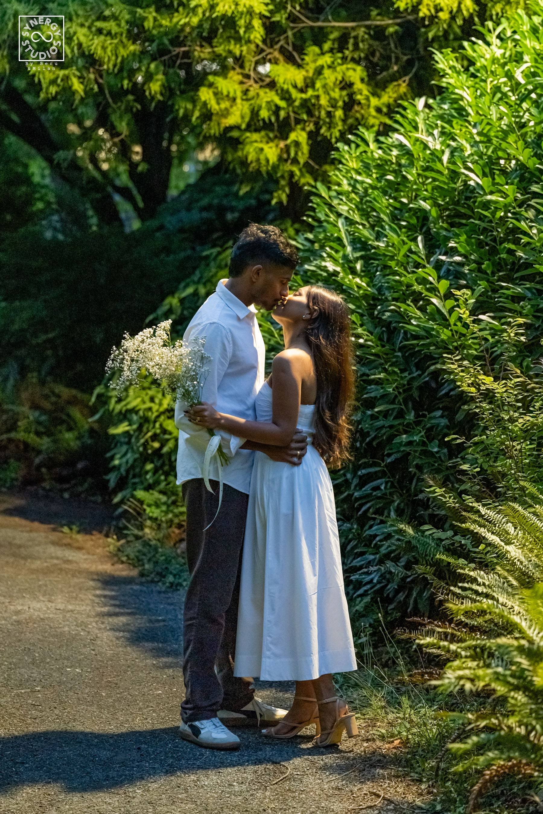 Couple embracing on a leafy garden path in warm evening light