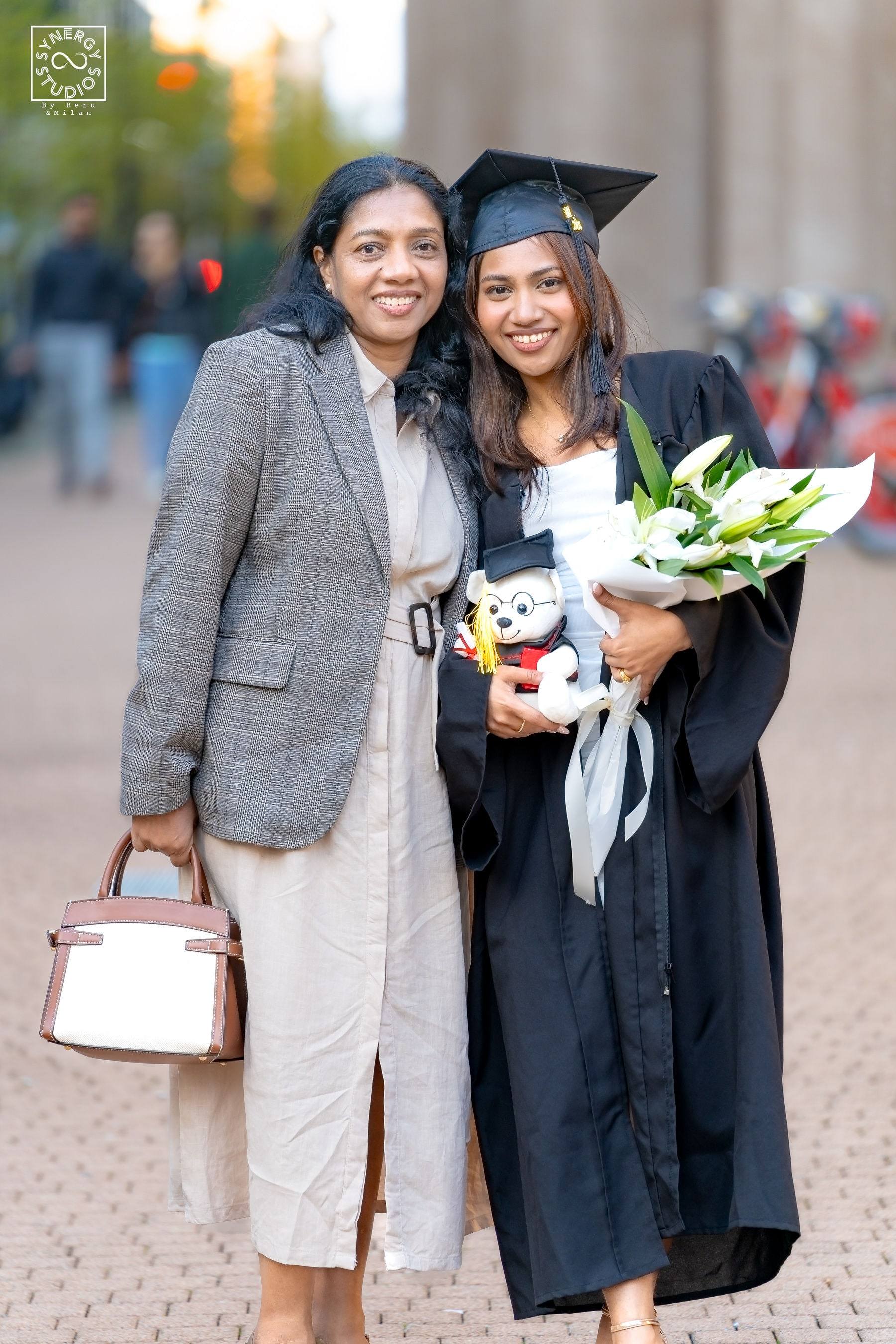 Graduate and her mother smiling together holding flowers