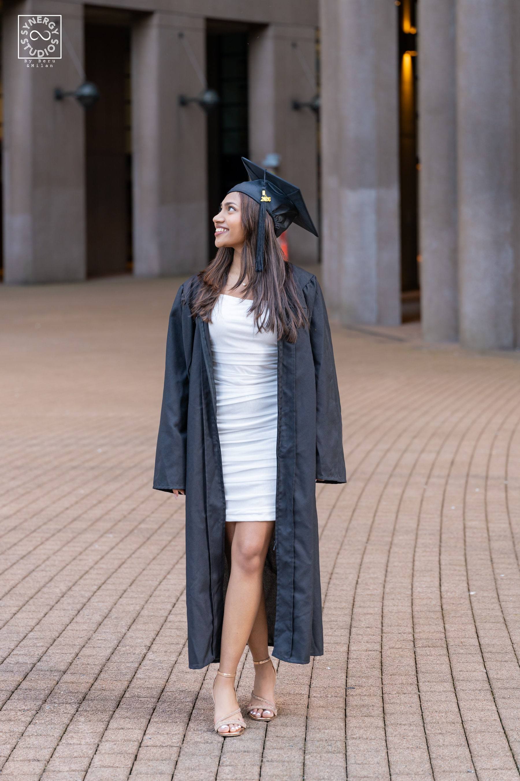 Full length portrait of a graduate walking across a campus courtyard