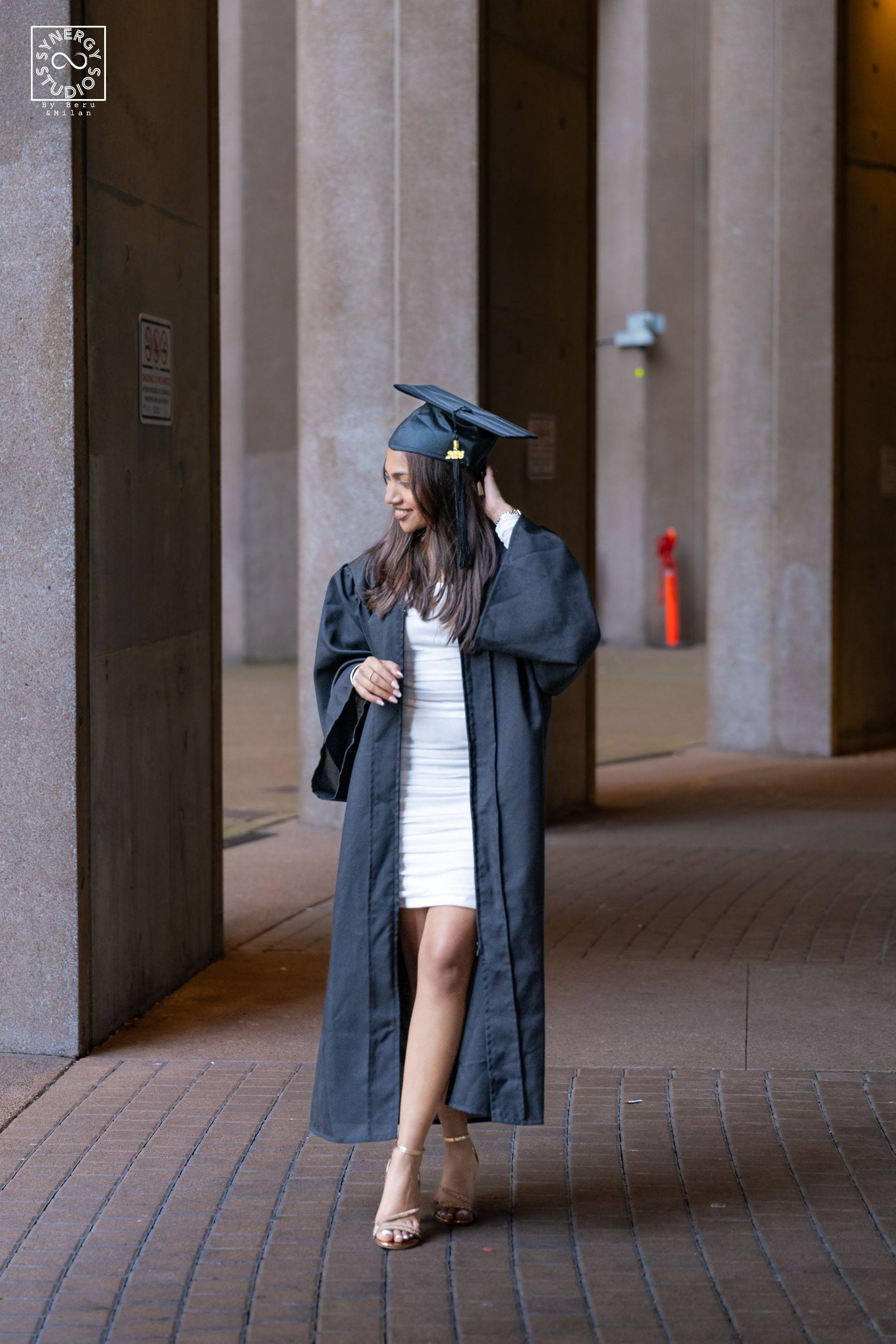 Graduate walking through a colonnade in her gown and cap