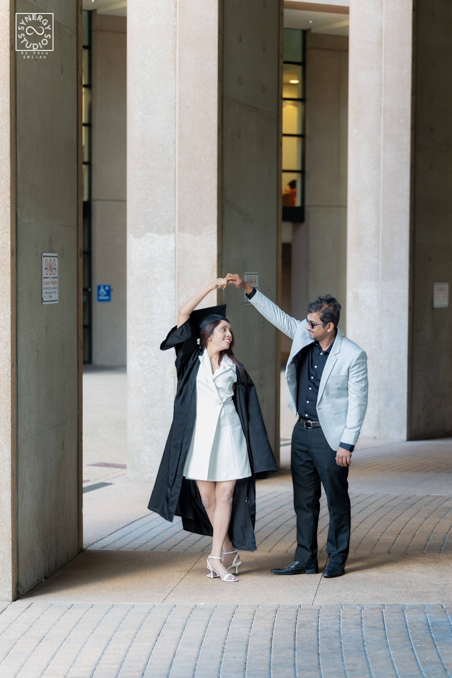 Couple holding a graduation cap together beneath an archway