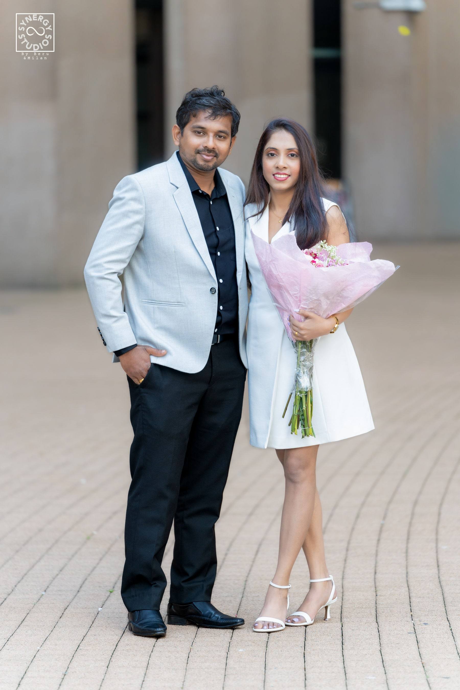 Graduate and her partner standing together with a pink bouquet