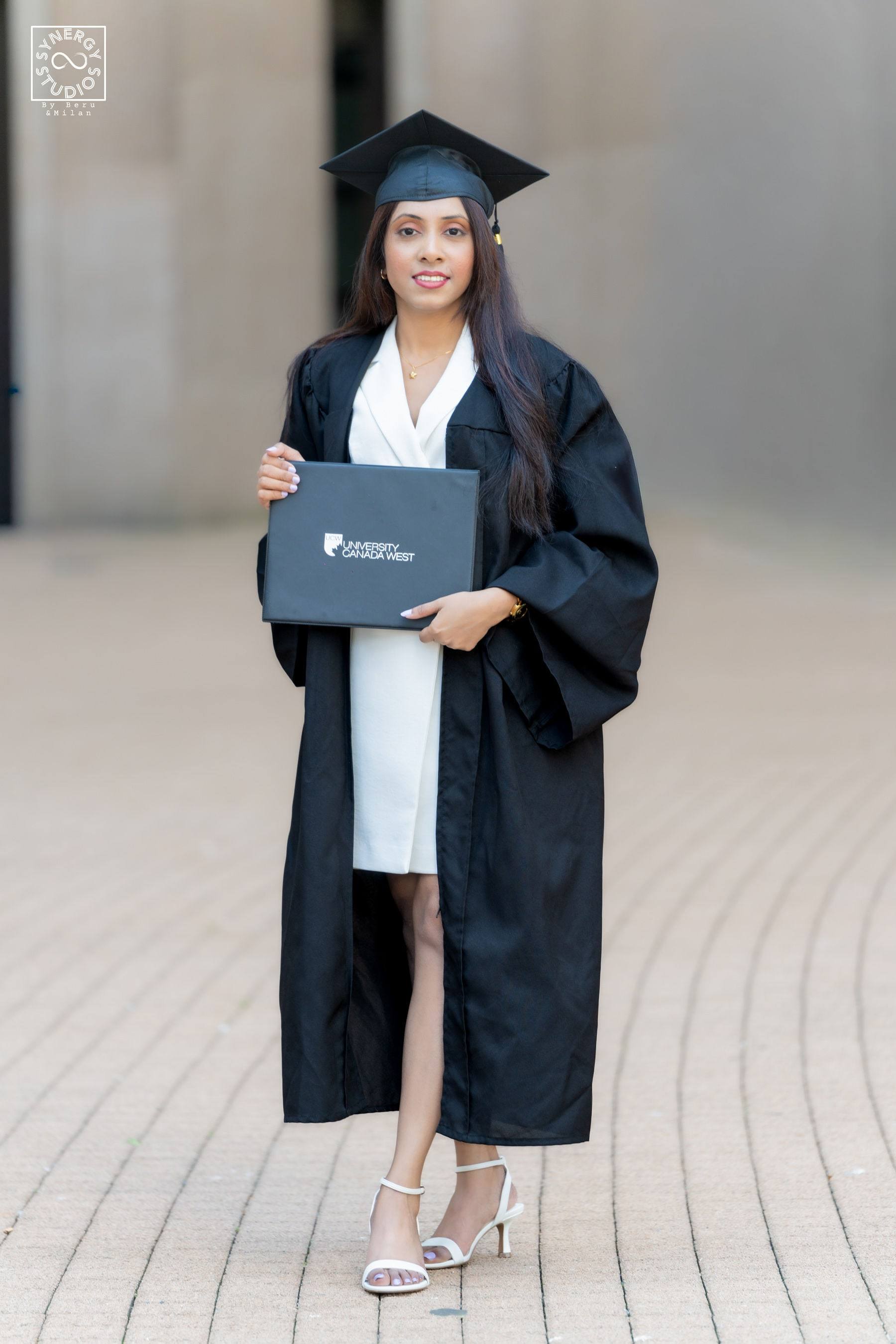 Graduate holding her diploma folder in front of stone columns