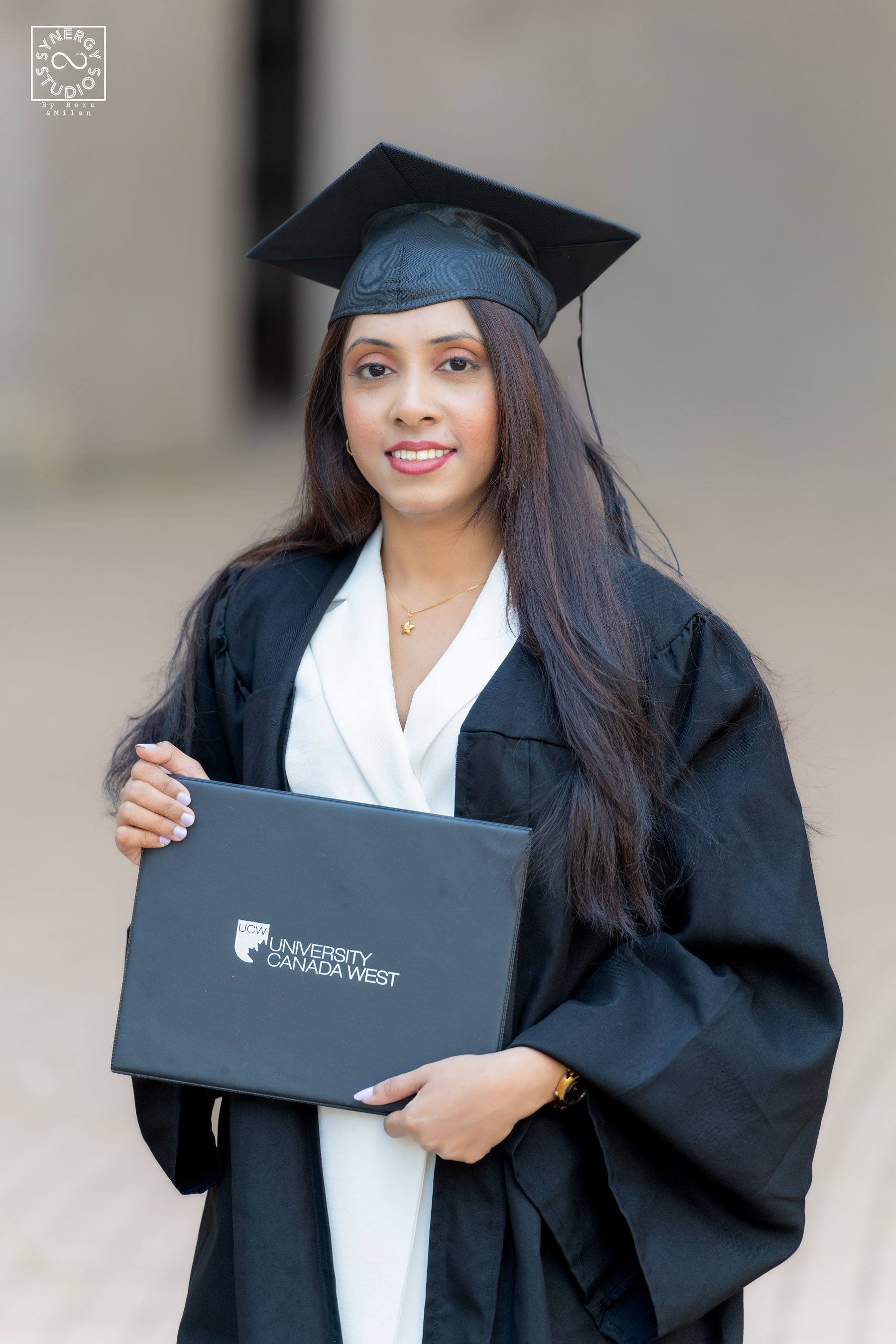 Close portrait of a smiling graduate holding her diploma folder
