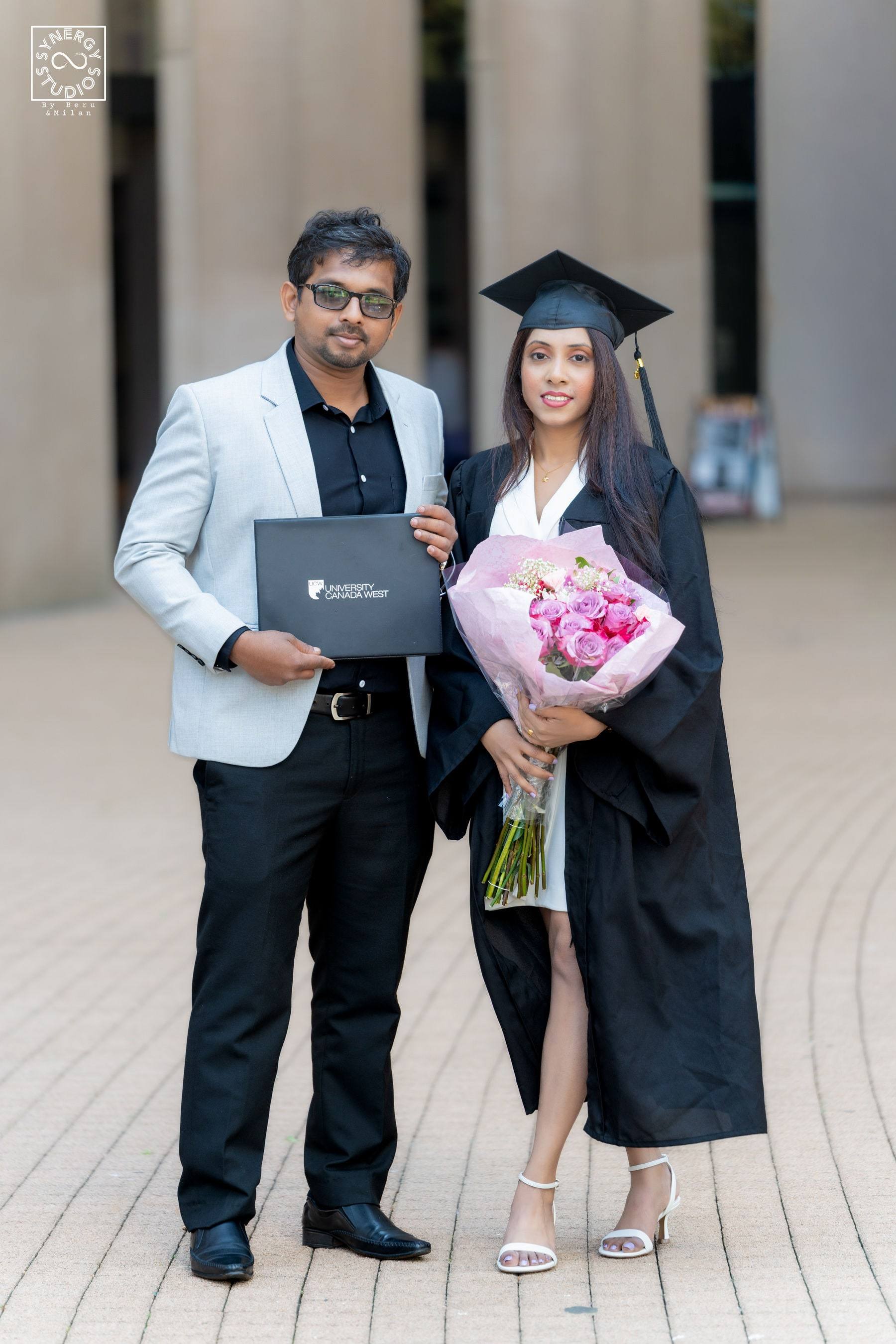 Graduate and her husband posing with her diploma and flowers