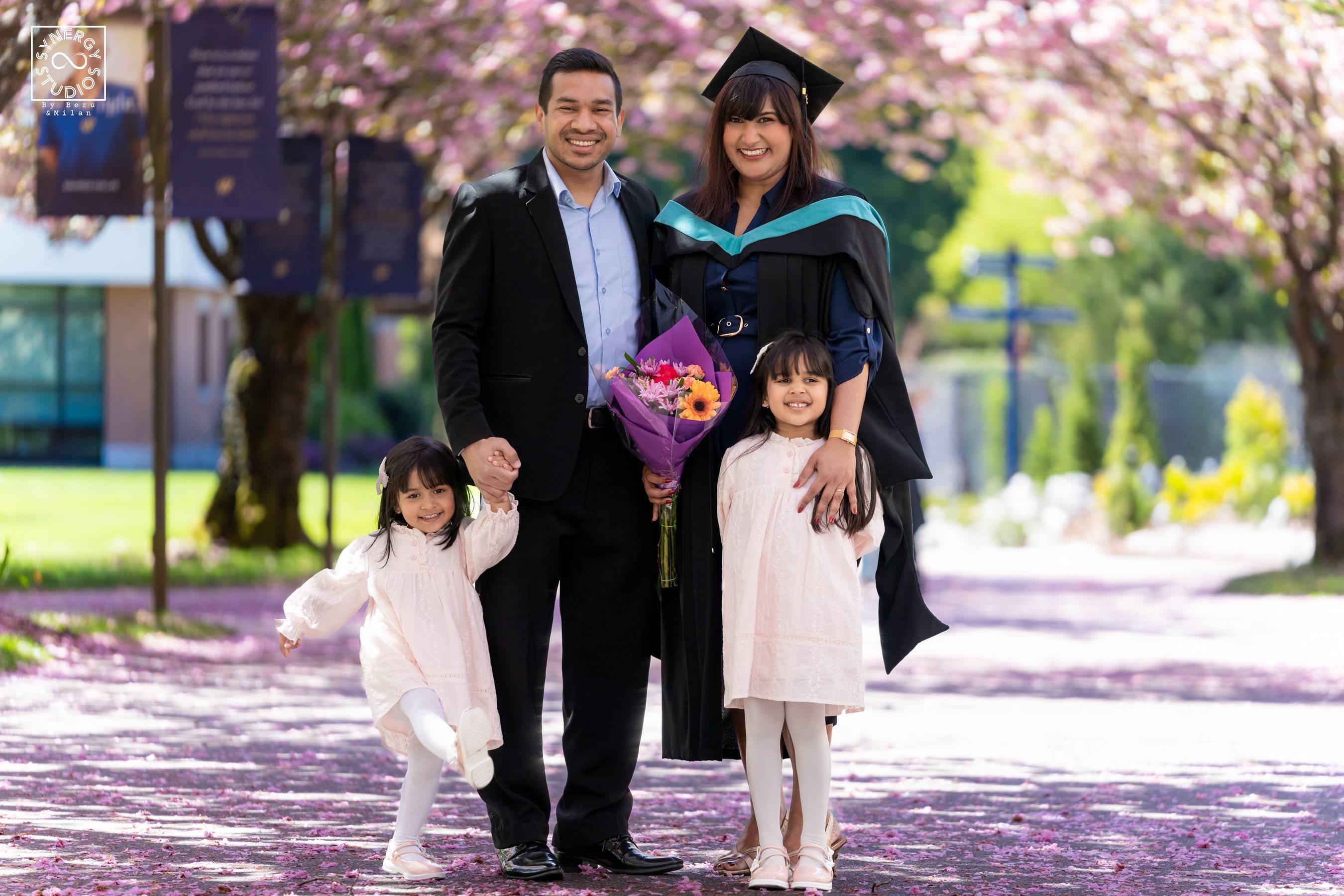 Graduate with her husband and two daughters under spring cherry blossoms
