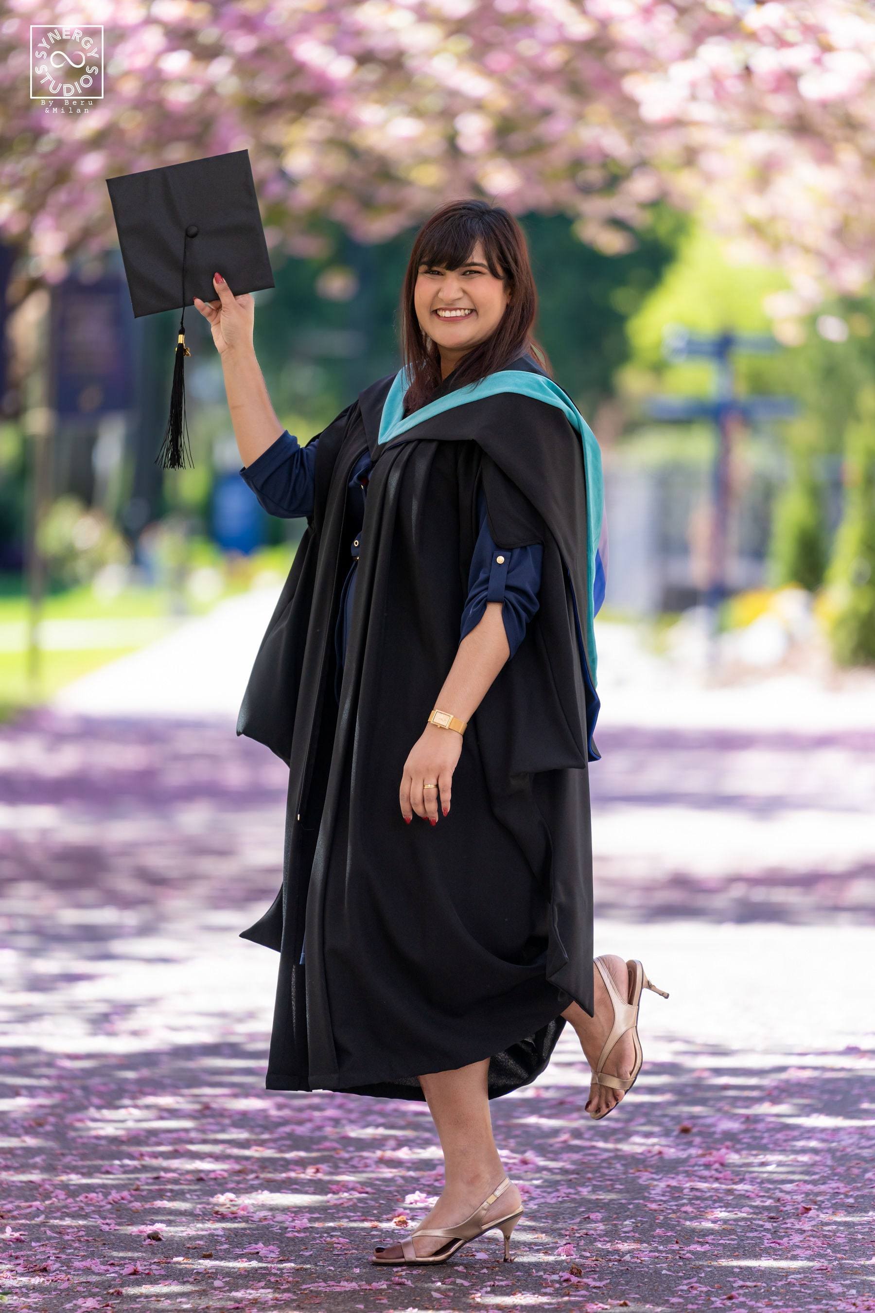 Graduate raising her diploma under cherry blossom trees