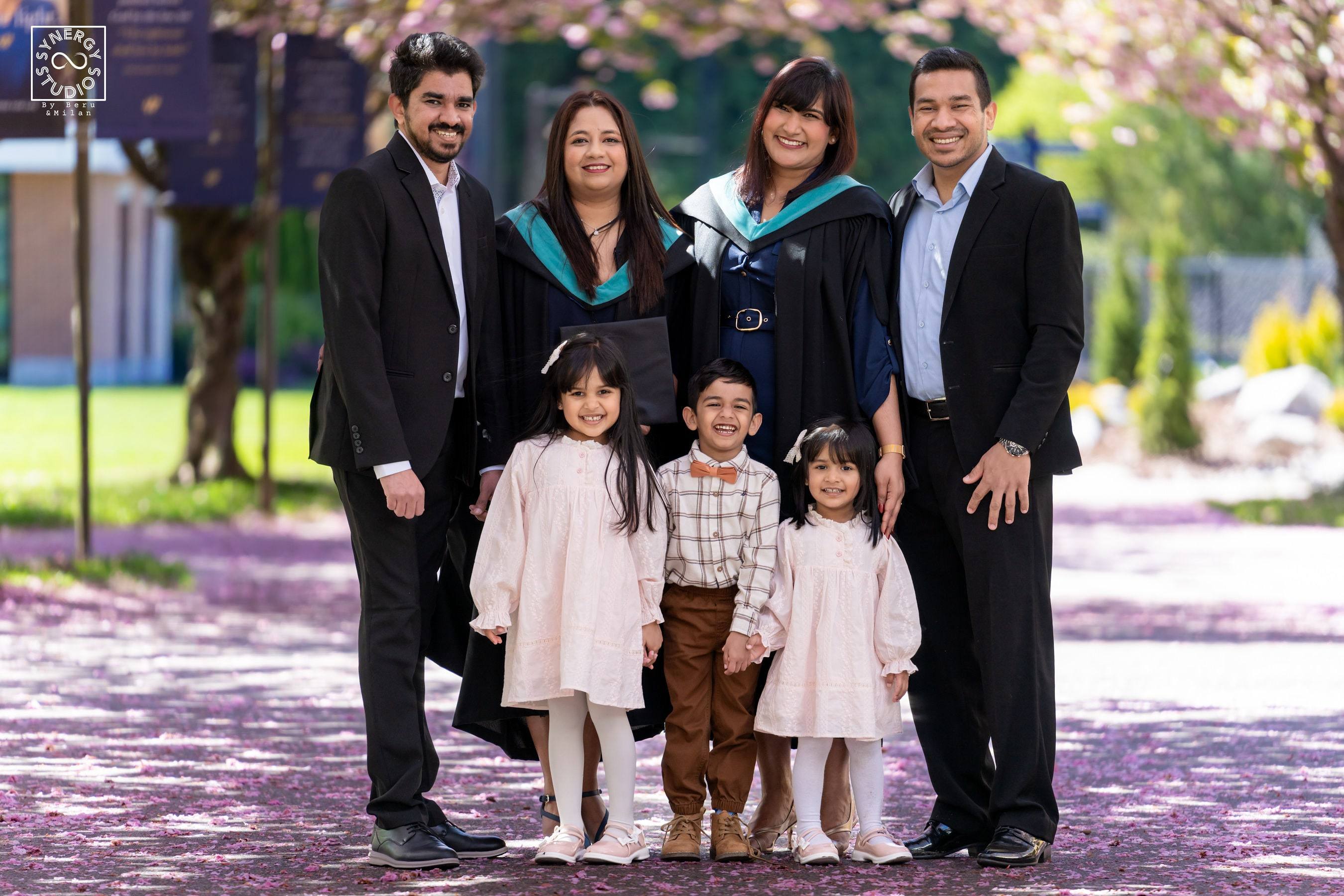 Extended family group portrait with the graduate under cherry blossoms