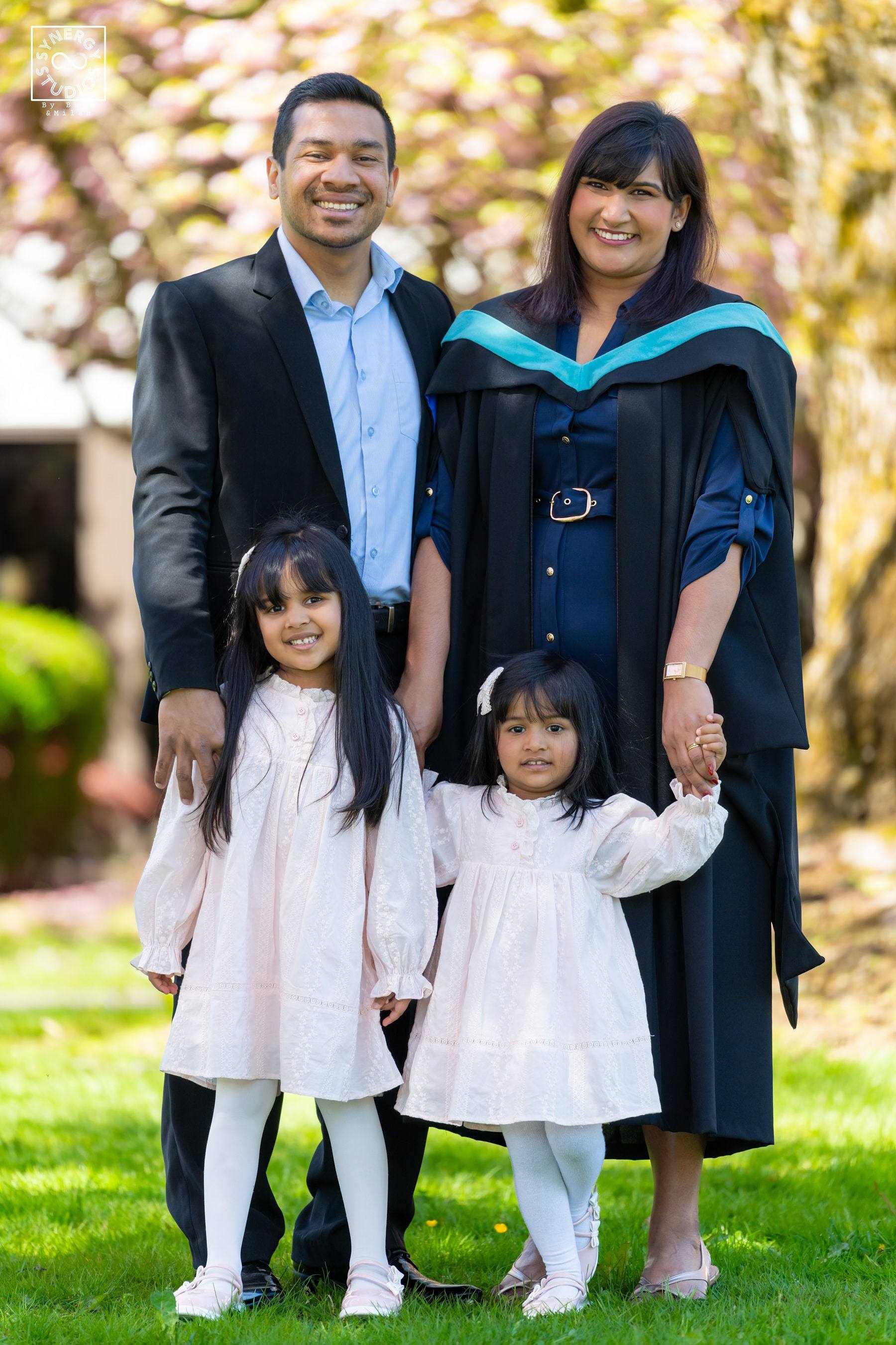 Graduate with her husband and daughters in front of a blossoming tree