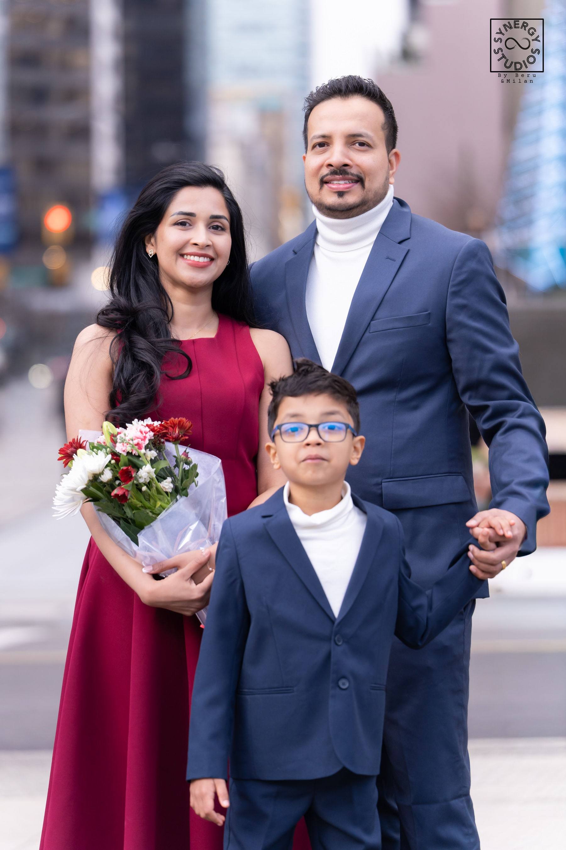 Graduate with her husband and son in front of city buildings