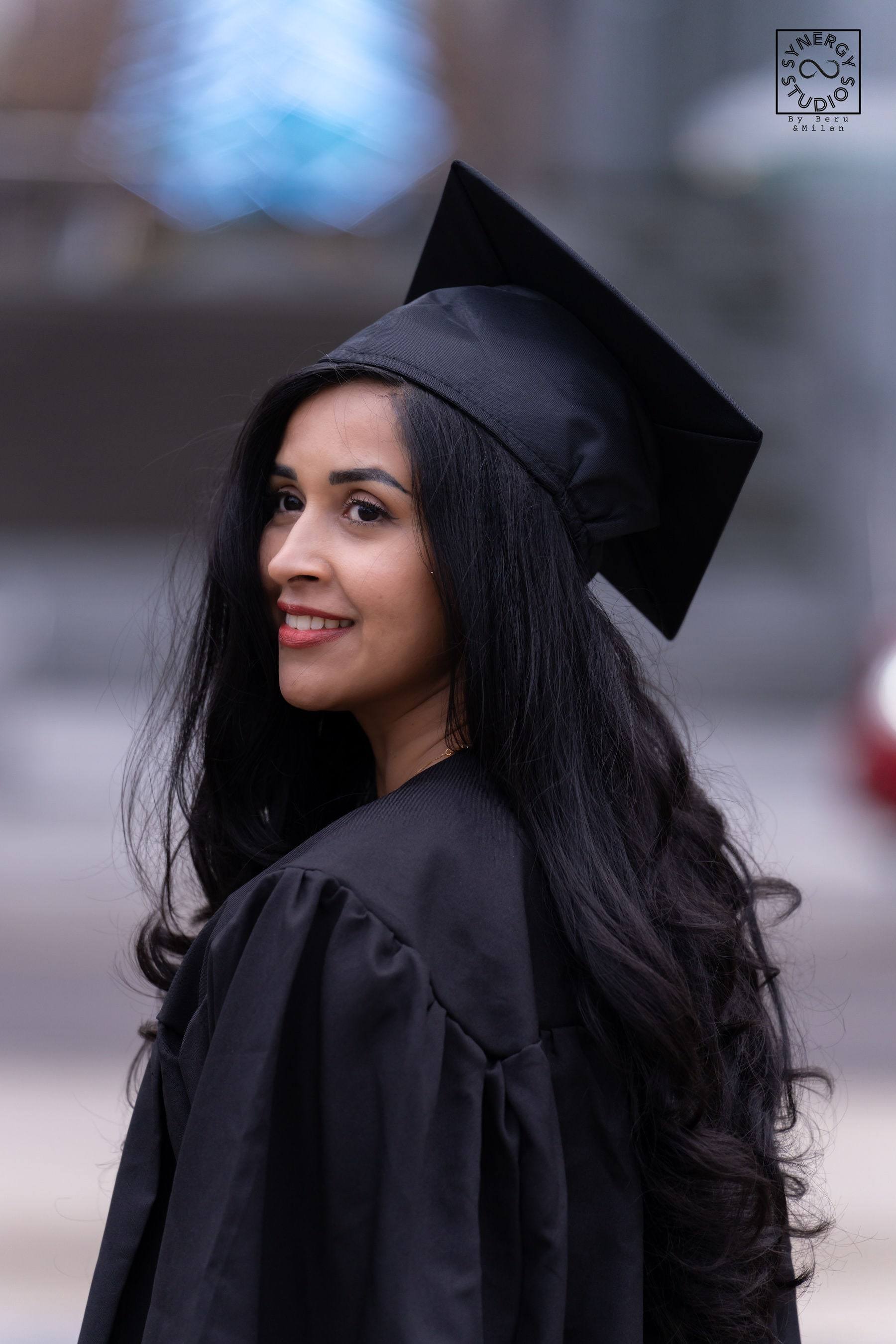 Side profile portrait of a graduate in her cap with the city softly blurred behind