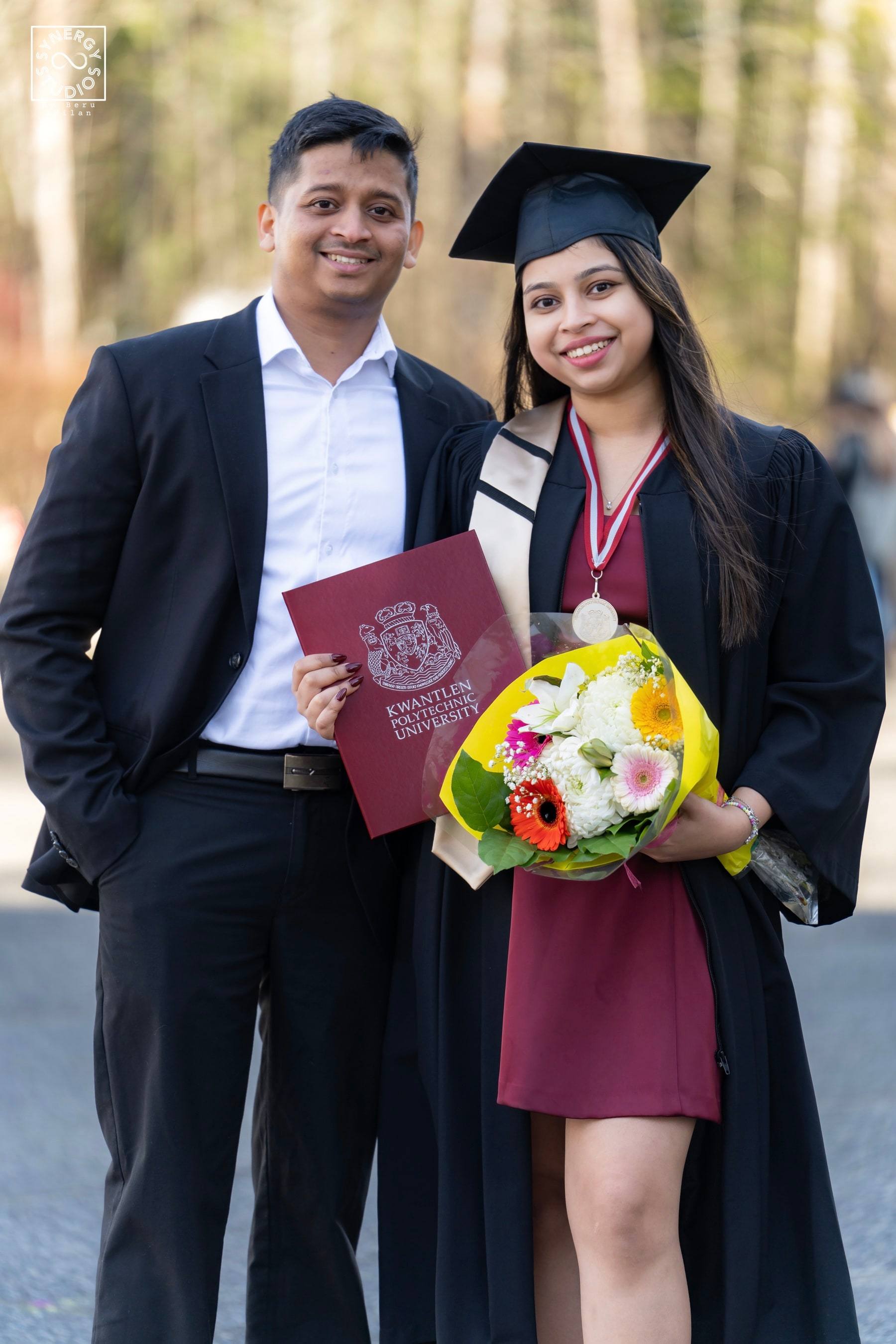 Graduate with her partner holding a bouquet and diploma folder