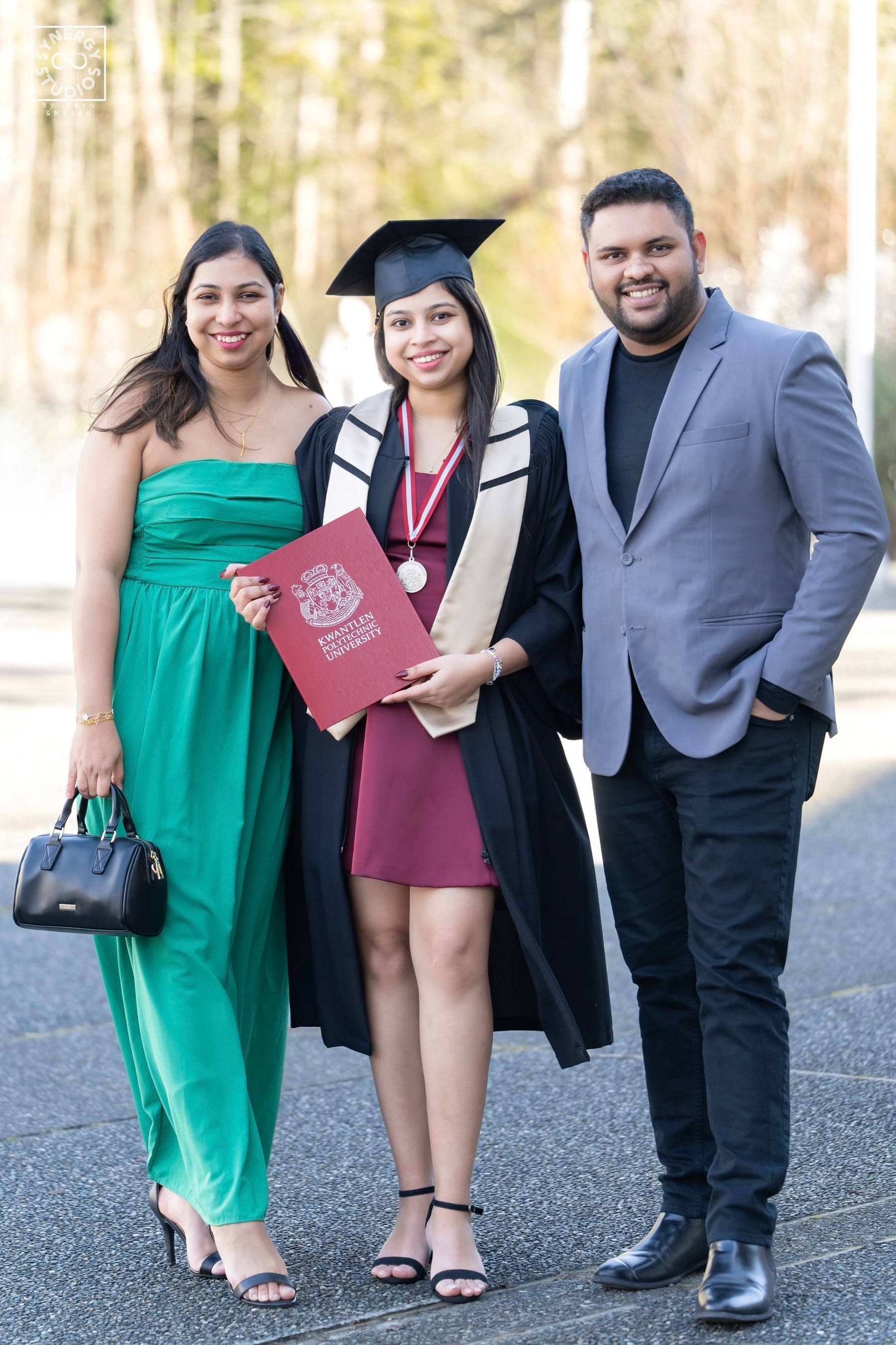 Graduate with two friends celebrating on campus